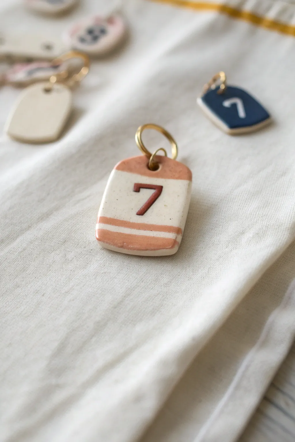 Soft-toned clay hockey jersey number tags with raised numerals, a chic minimalist charm idea.