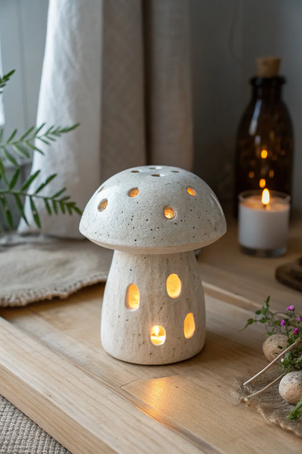 Softly glowing mushroom tealight luminary in speckled clay, cozy minimal Scandinavian vibes.