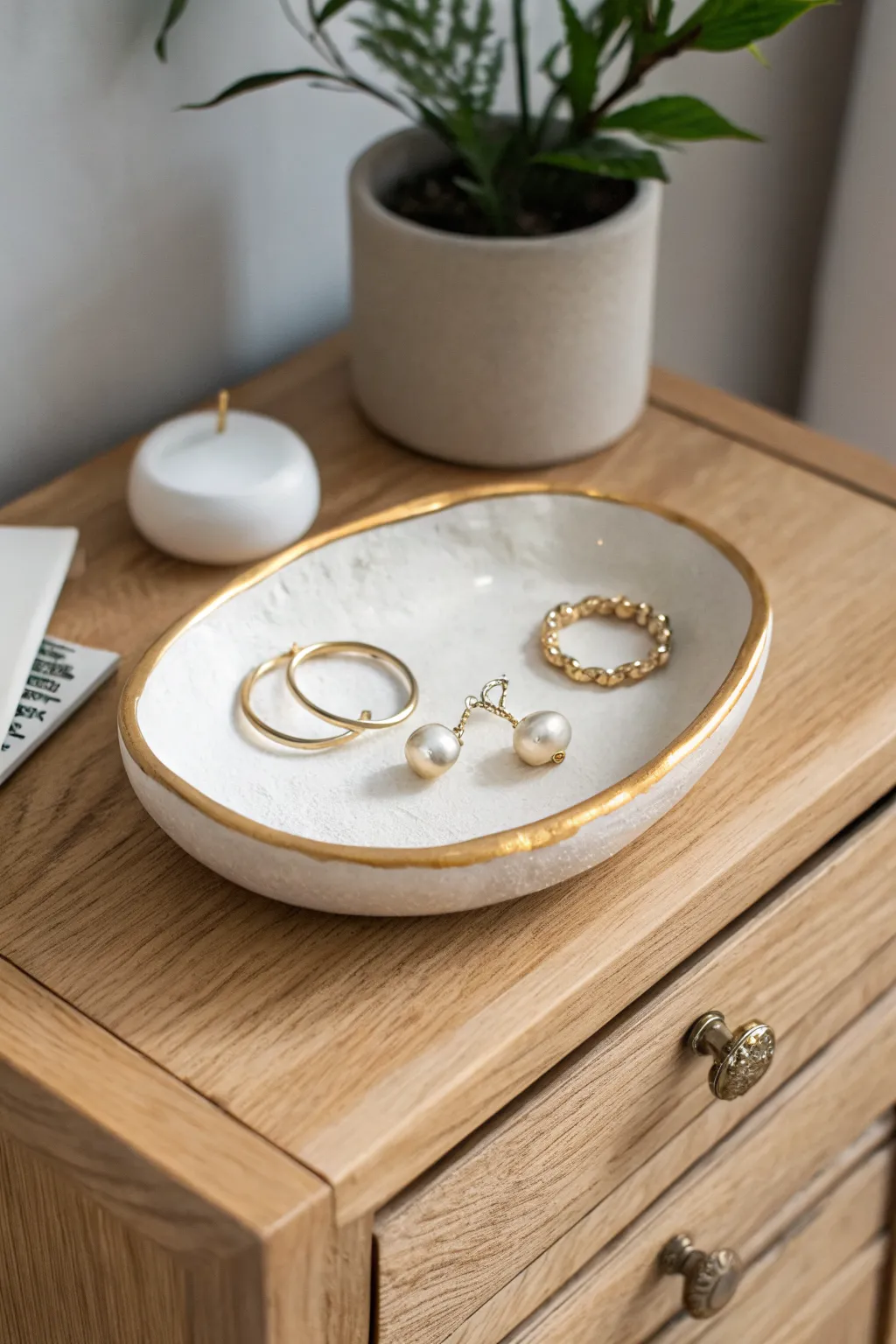 Minimal oval polymer clay jewelry dish with a chic gold rim, calm Scandinavian nightstand styling