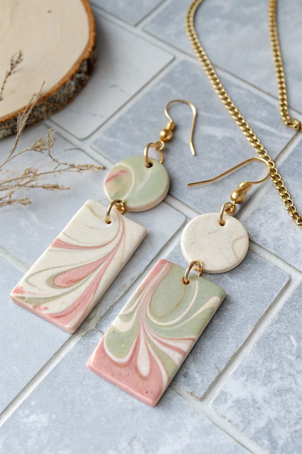 Soft marbled polymer clay slab earrings in cream, blush, and sage on a stone tile backdrop