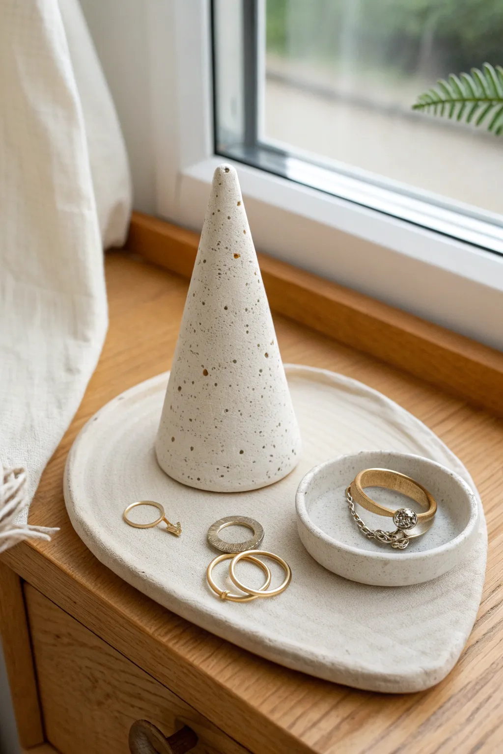Minimal air dry clay ring cone on a nightstand, with a tiny dish for sparkle storage.