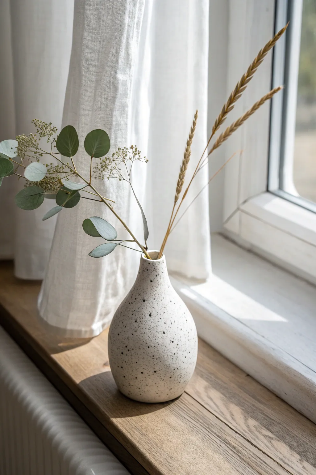 A simple handmade bud vase, sunlit on the sill, perfect for one or two delicate stems.