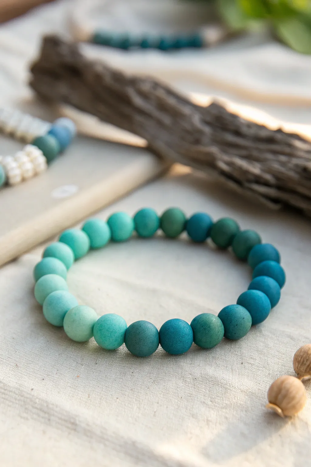 Monochrome teal ombré clay bead bracelet, from pale aqua to deep ocean teal in soft daylight.