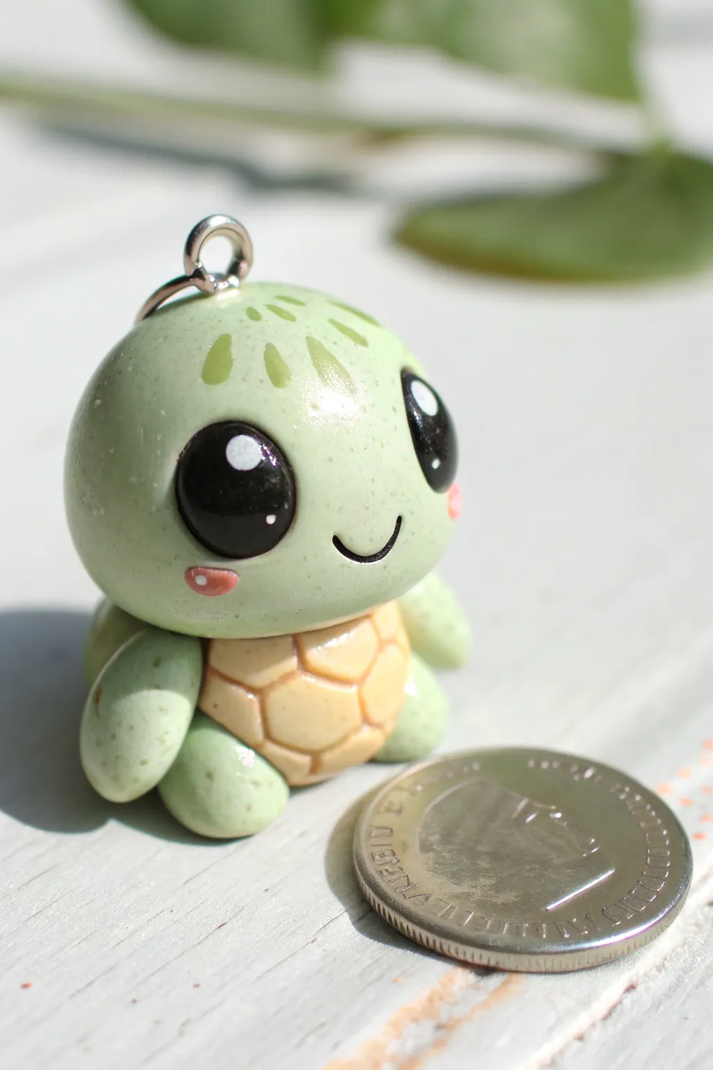 Kawaii turtle clay charm with big glossy eyes, shown beside a coin on a clean bright backdrop