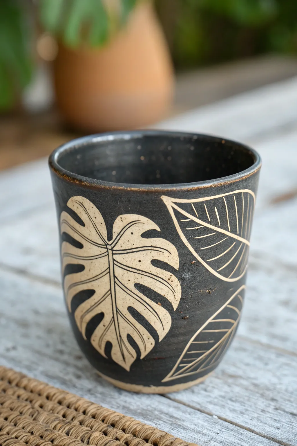 Minimal two-color sgraffito cup with a bold leaf silhouette under clear glaze shine