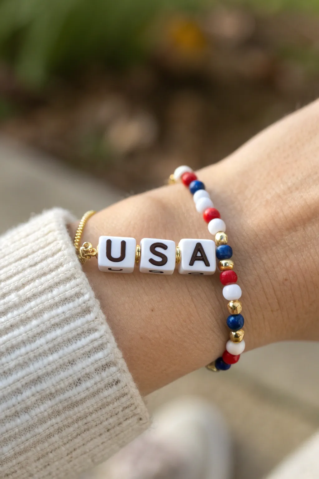 Patriotic clay bead bracelet with USA letter beads, gold spacers, and bold red white blue beads