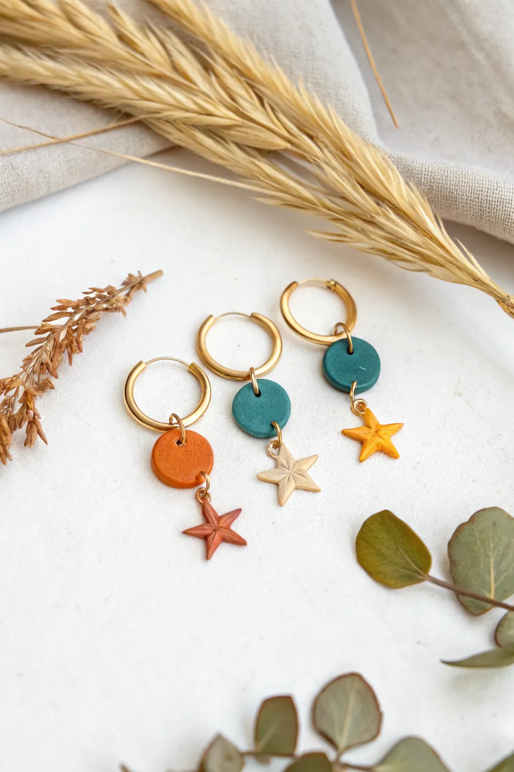 Minimalist hoop earrings with colorful air-dry clay mini charms and soft dried botanicals.