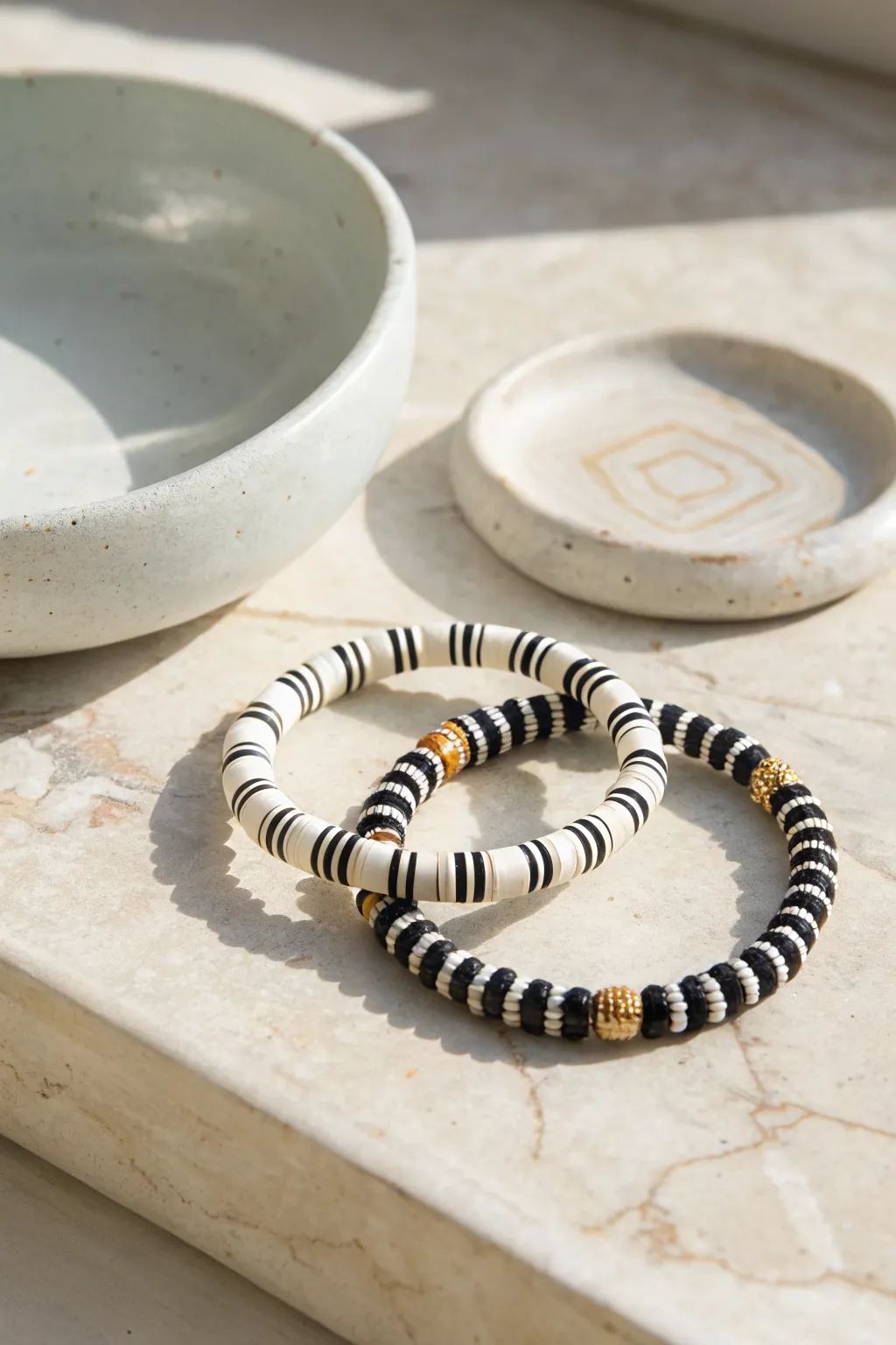 Minimal black-and-white clay bead bracelets with tiny gold spacers, simple and striking