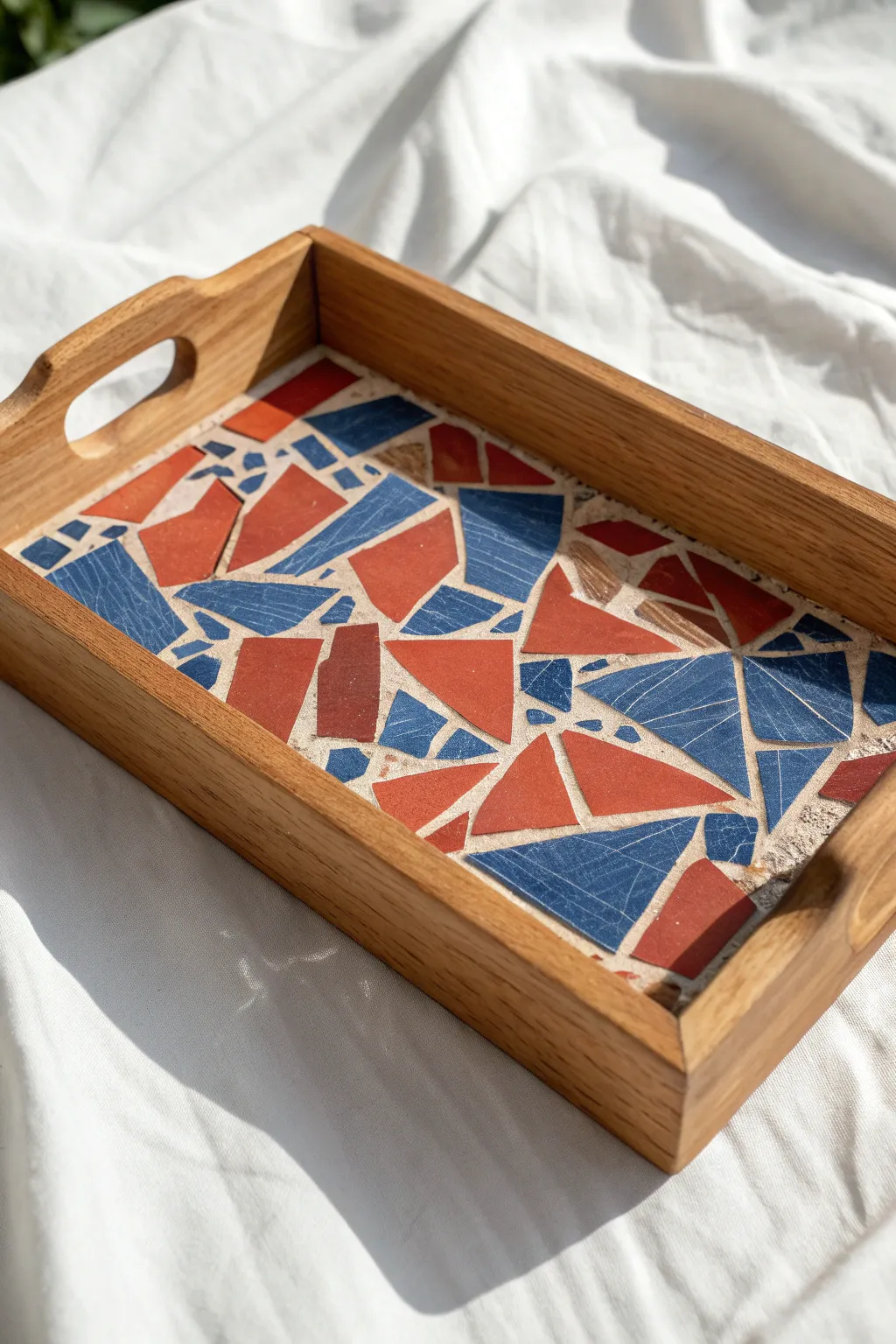 Minimalist oak serving tray insert with bold broken-plate mosaic and smooth white grout finish.