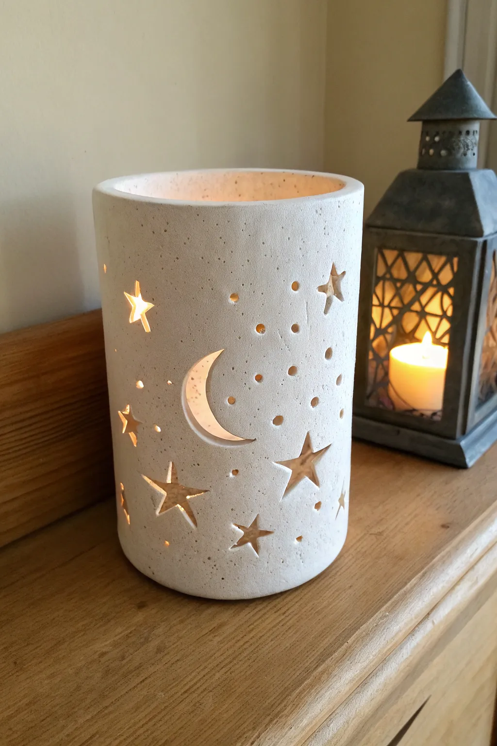Warm candlelit ceramic lantern with star and moon cut-outs casting dreamy shadows.