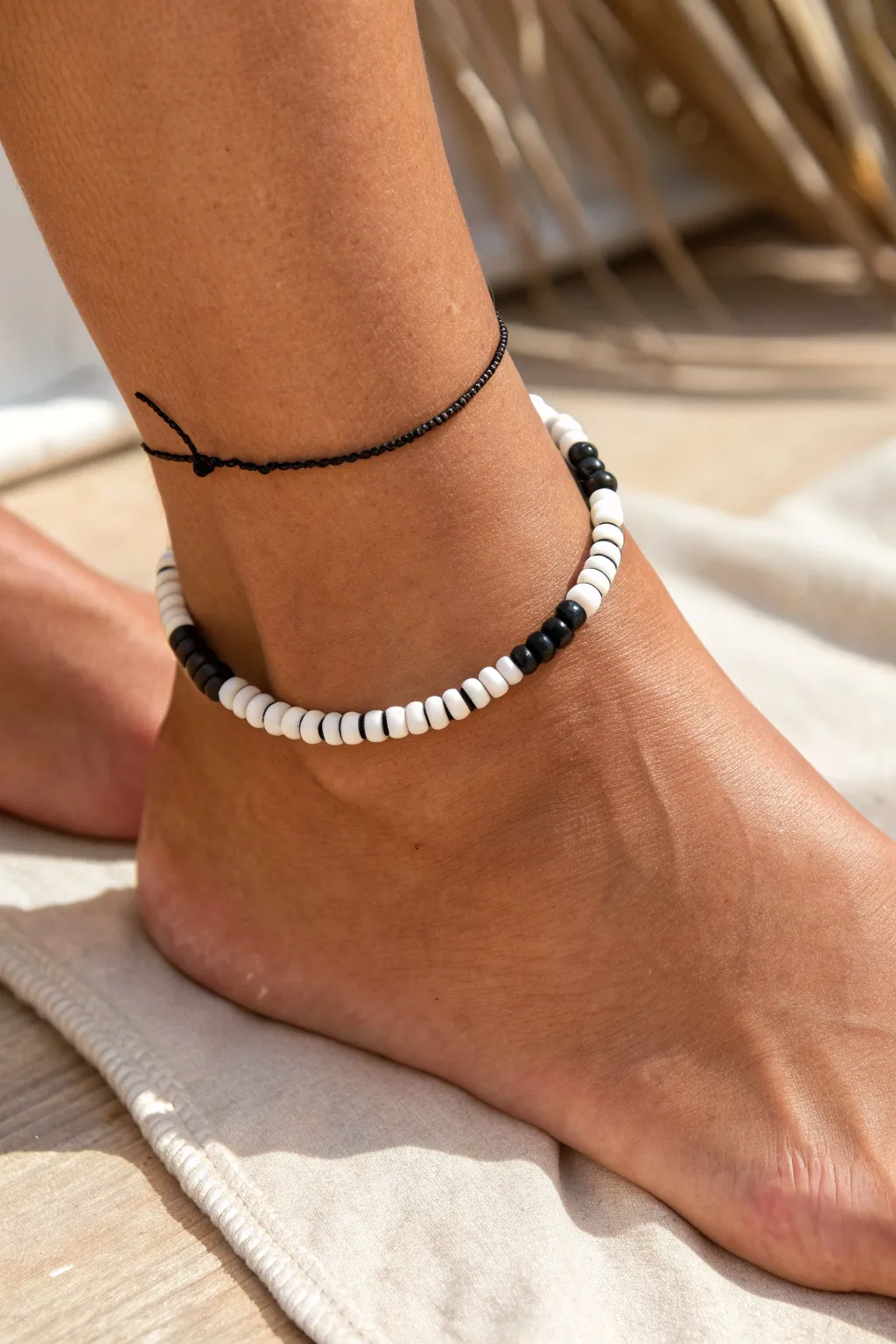 Graphic black and white heishi clay bead anklet, minimalist and bold against warm skin.