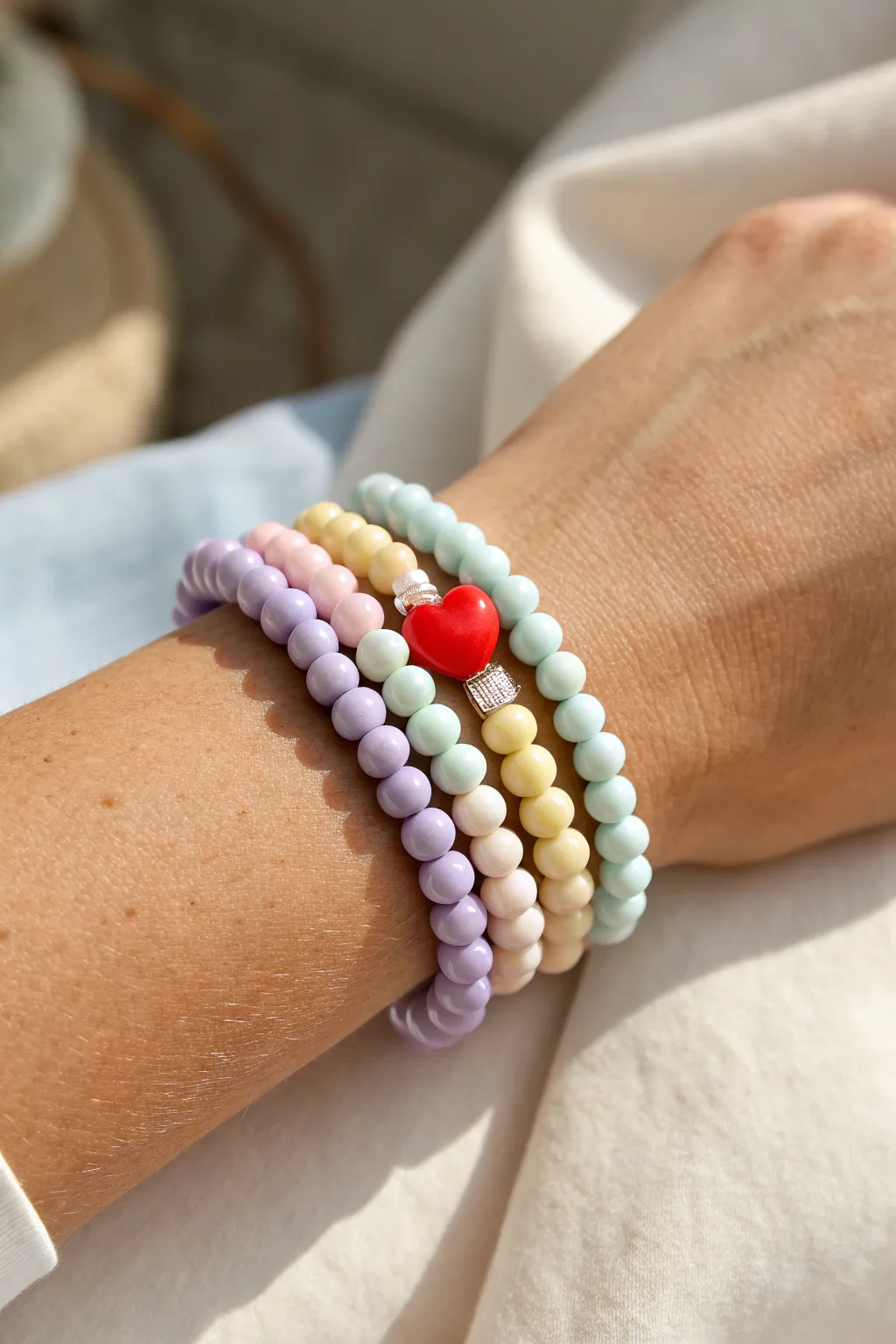 Pastel rainbow clay bracelet stack with one bold red heart bead for a sweet focal pop.