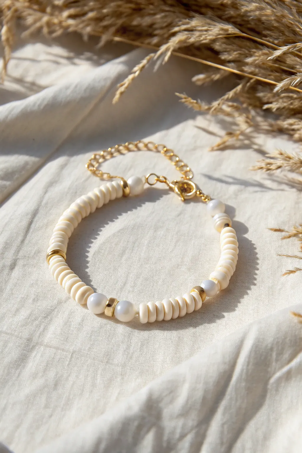 Minimal white clay disc and pearl bracelet on linen with soft shadows for a calm, modern look.