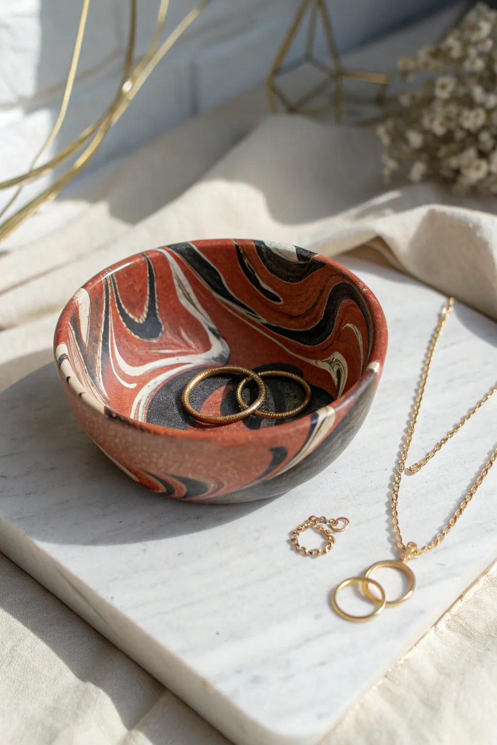 Glossy marbled polymer clay bowl with gold jewelry for a chic, minimalist boho finish