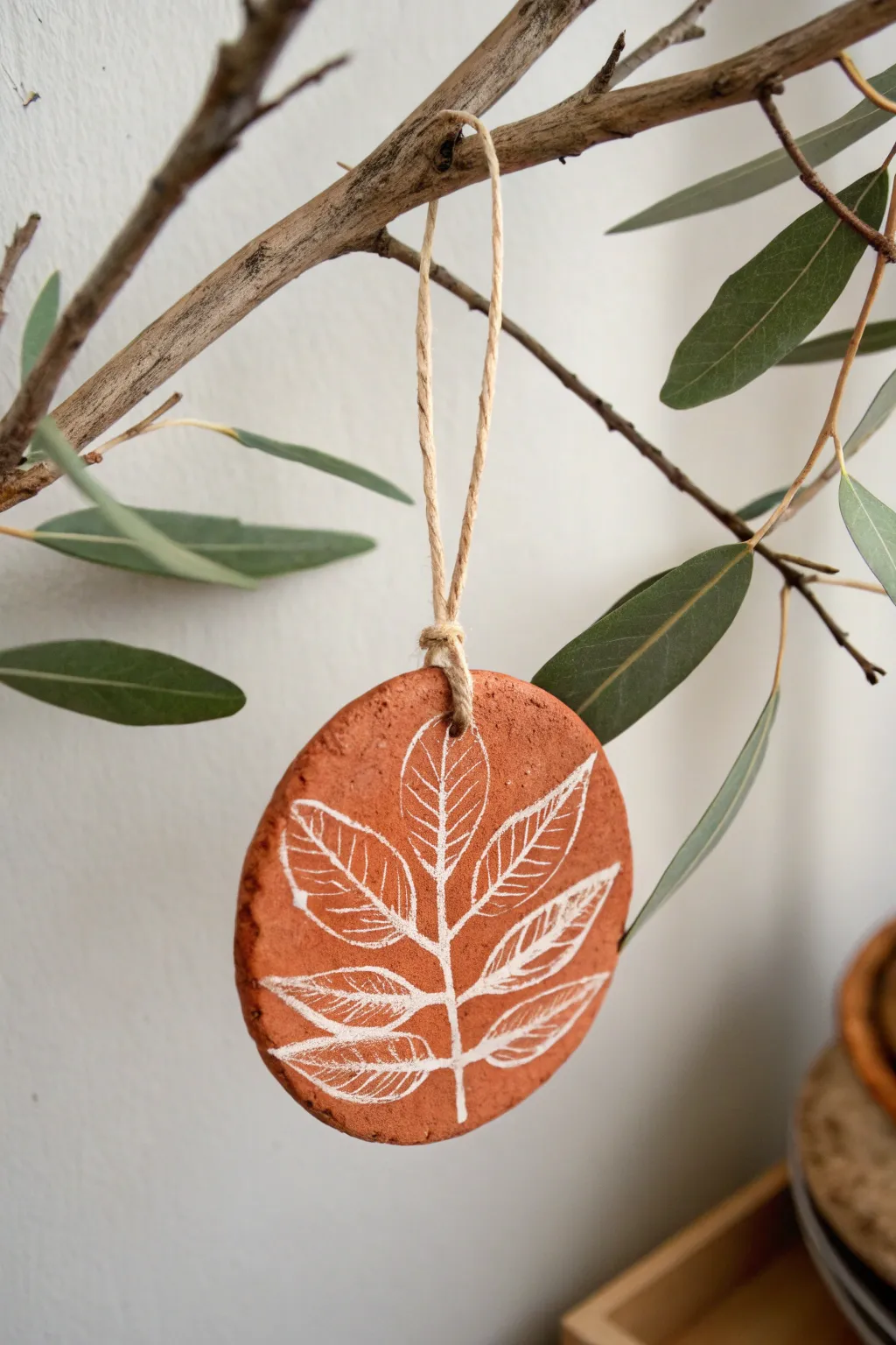Minimal leaf-imprint clay ornament with twine hanger, warm terracotta tones, clean Nordic styling