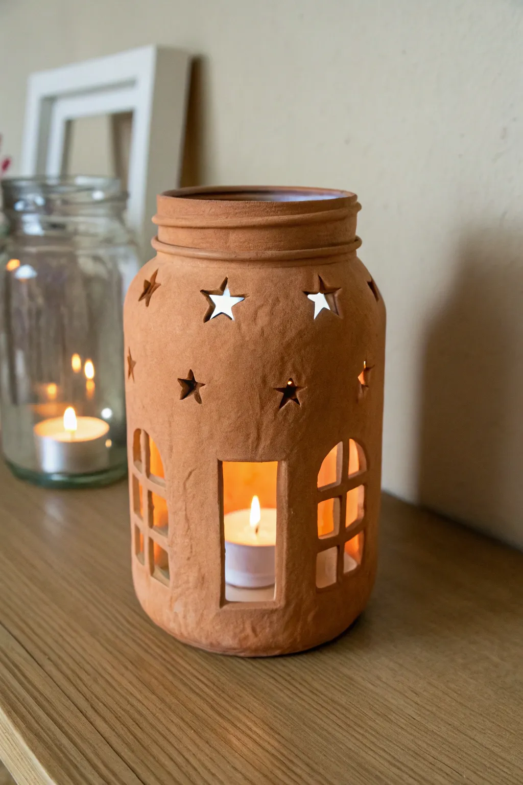 Simple clay lantern jar with star and square cutouts, glowing warmly in a cozy dim corner