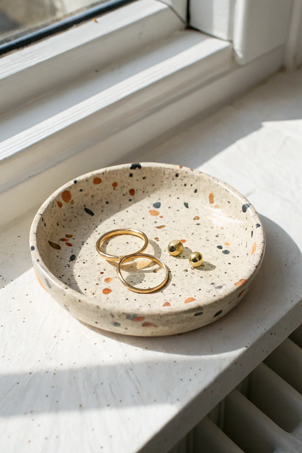 Speckled terrazzo jewelry dish in ivory clay, a bright minimalist accent for earrings and bracelets.