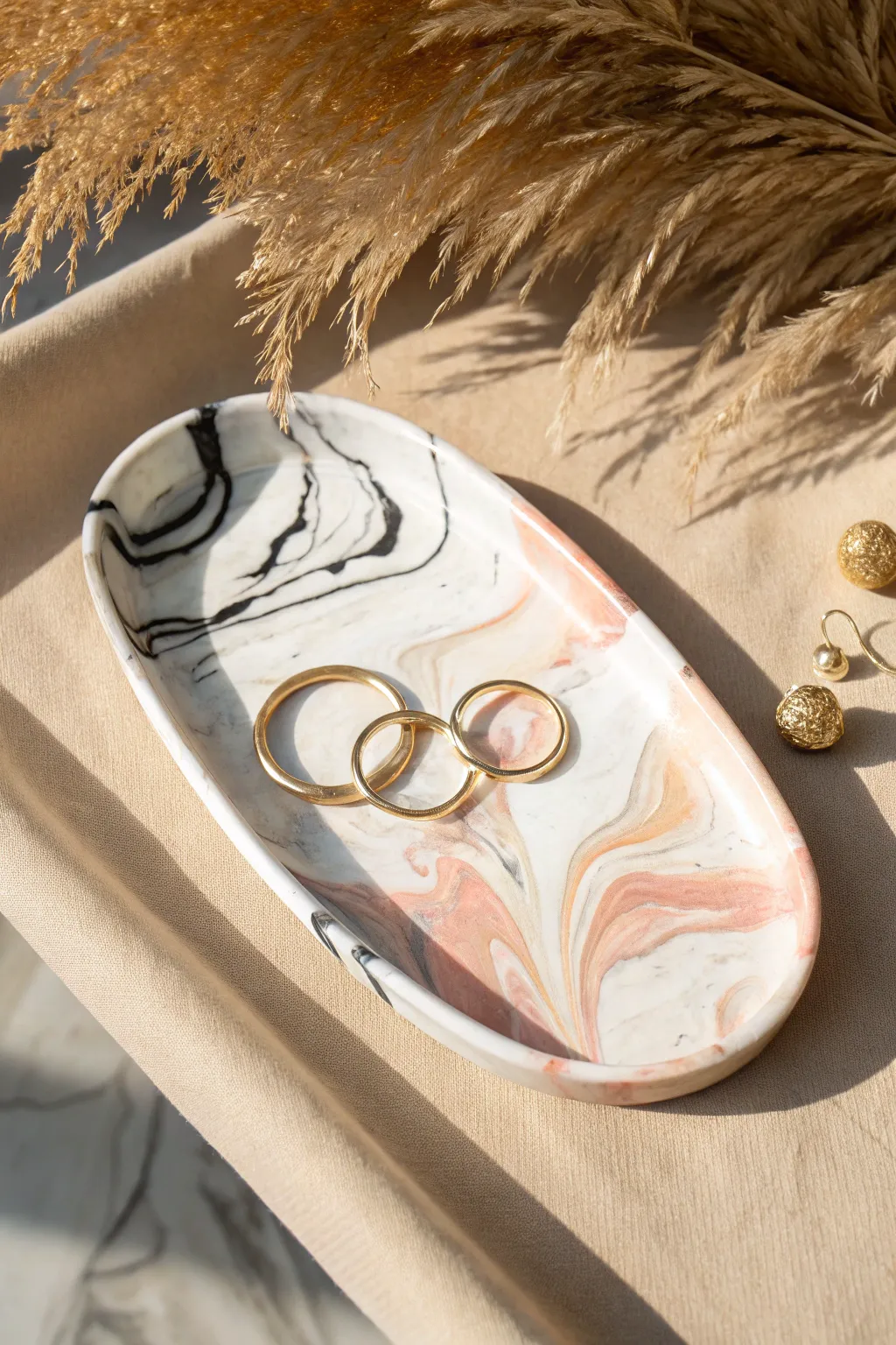 Marbled swirl clay jewelry tray with glossy finish and gold rings, minimal yet bold.