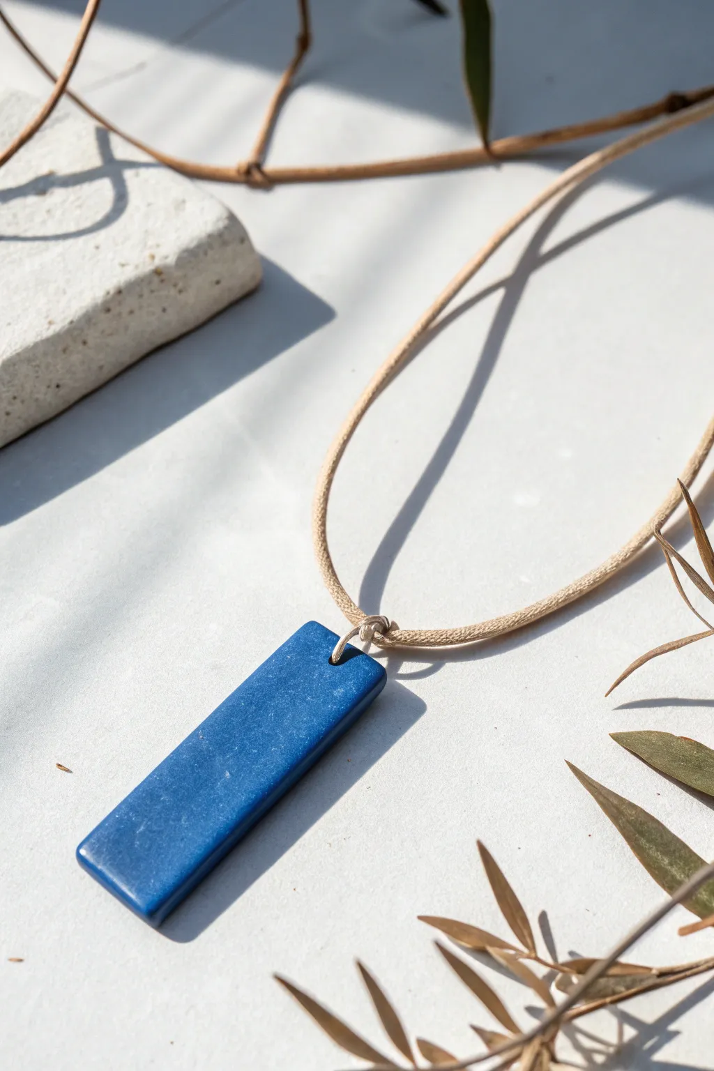 Sleek cobalt clay bar pendant on linen cord, a crisp minimalist necklace with a soft satin glow.
