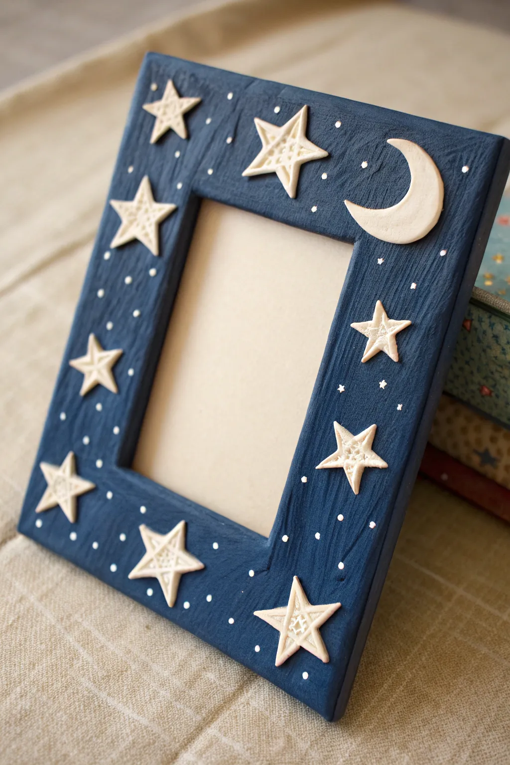 Dreamy starry-night clay frame in deep indigo with raised moon and stars, minimal boho vibe.