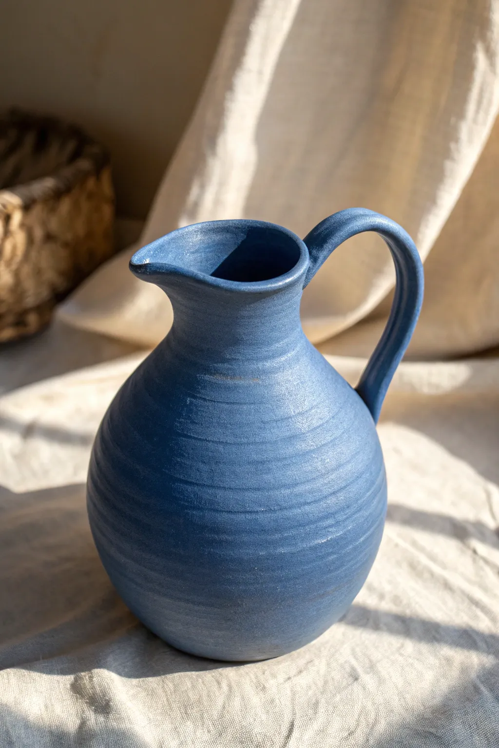 Soft-curved pinch-and-coil pitcher in bold matte blue, Nordic minimal style with handmade warmth.