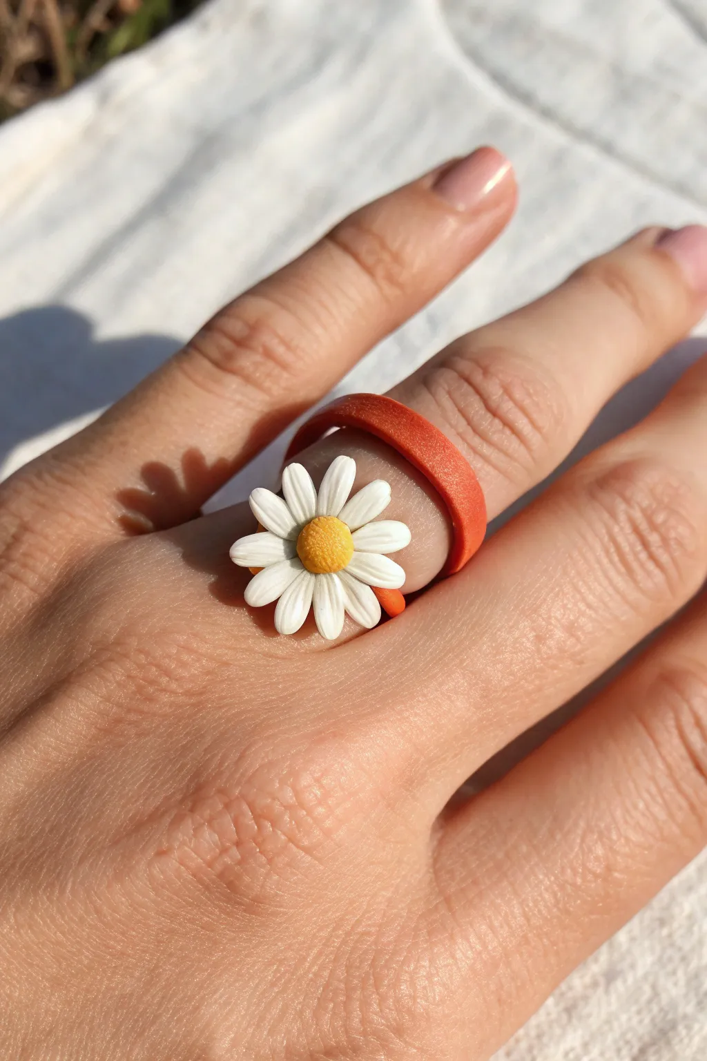 Cheerful clay daisy ring idea: simple white petals and sunny yellow center in bright daylight.