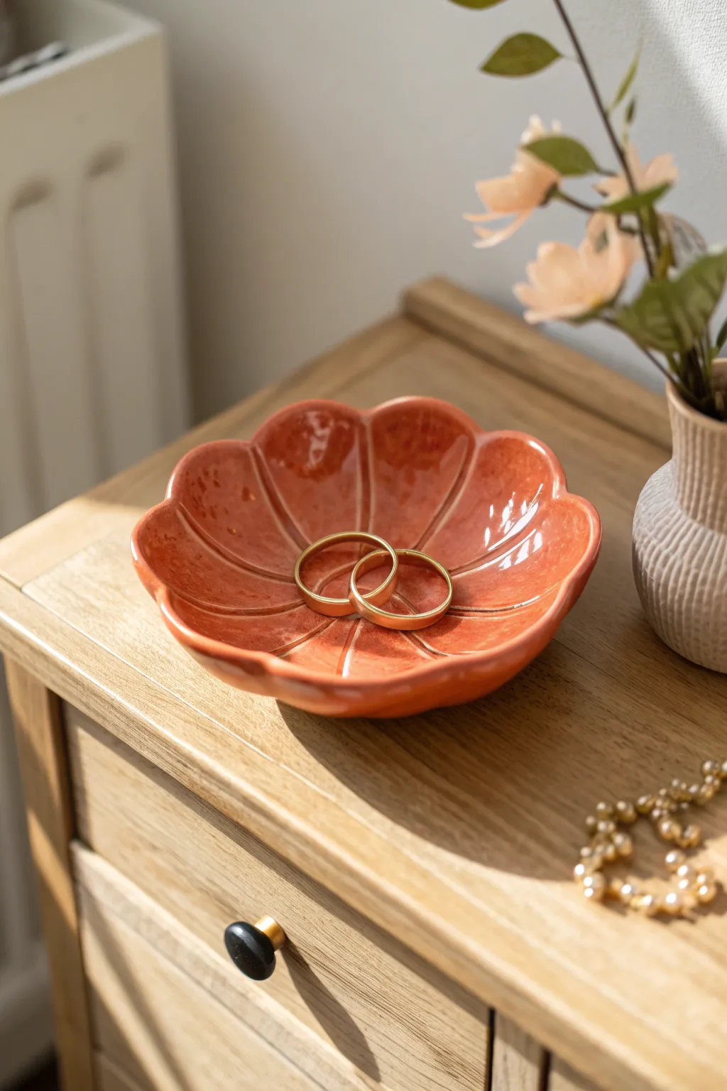 Glossy flower jewelry dish cradling rings, a cozy minimalist bedside accent in bold color.