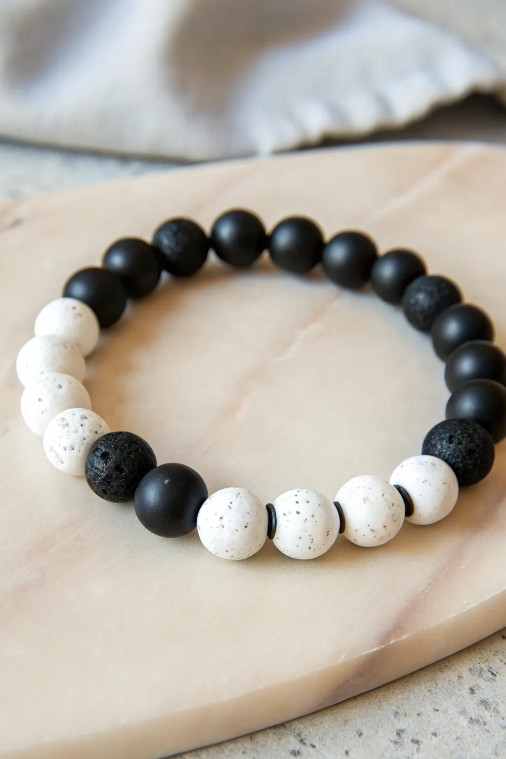 Bold black-and-white clay bead bracelet flat lay with graphic contrast and simple handmade rhythm.