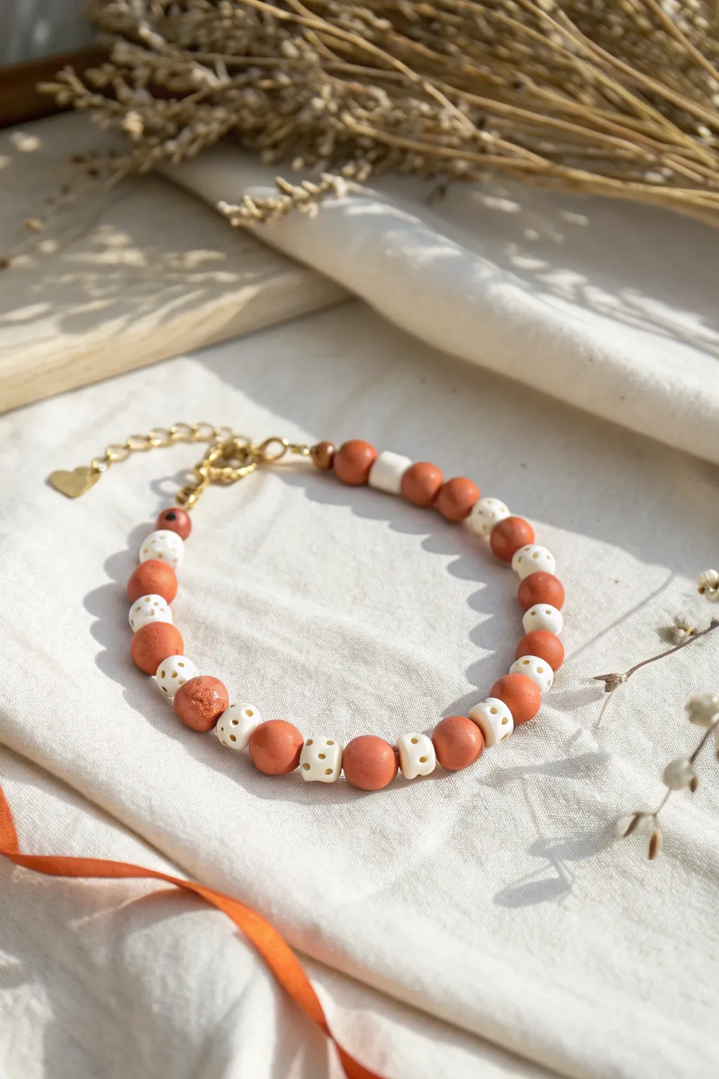 Sweet clay bead bracelet with tiny heart accents, minimalist boho style in bright natural light.