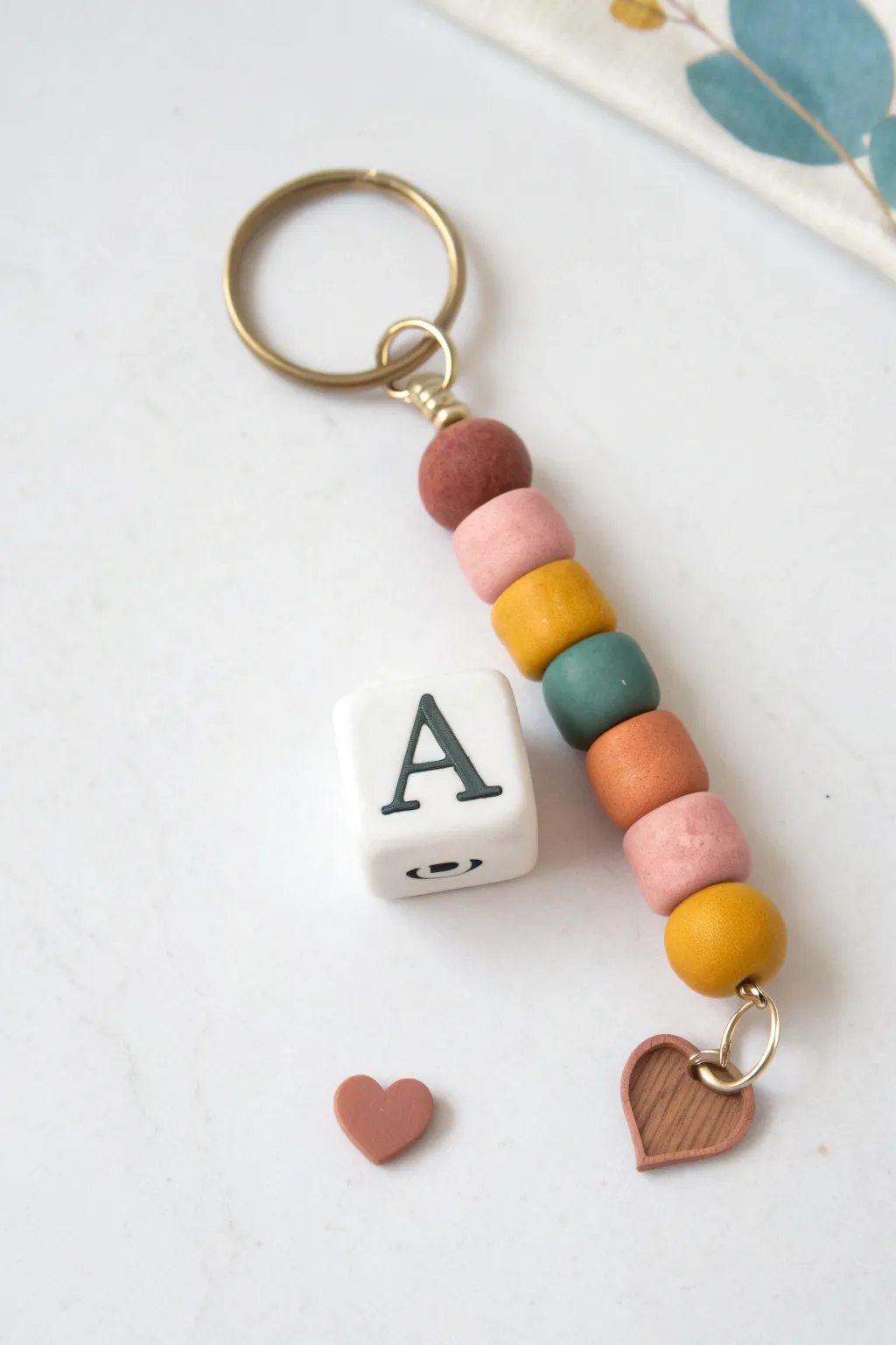 Minimal clay bead keychain with a bold initial and tiny heart charm, sweet and modern.