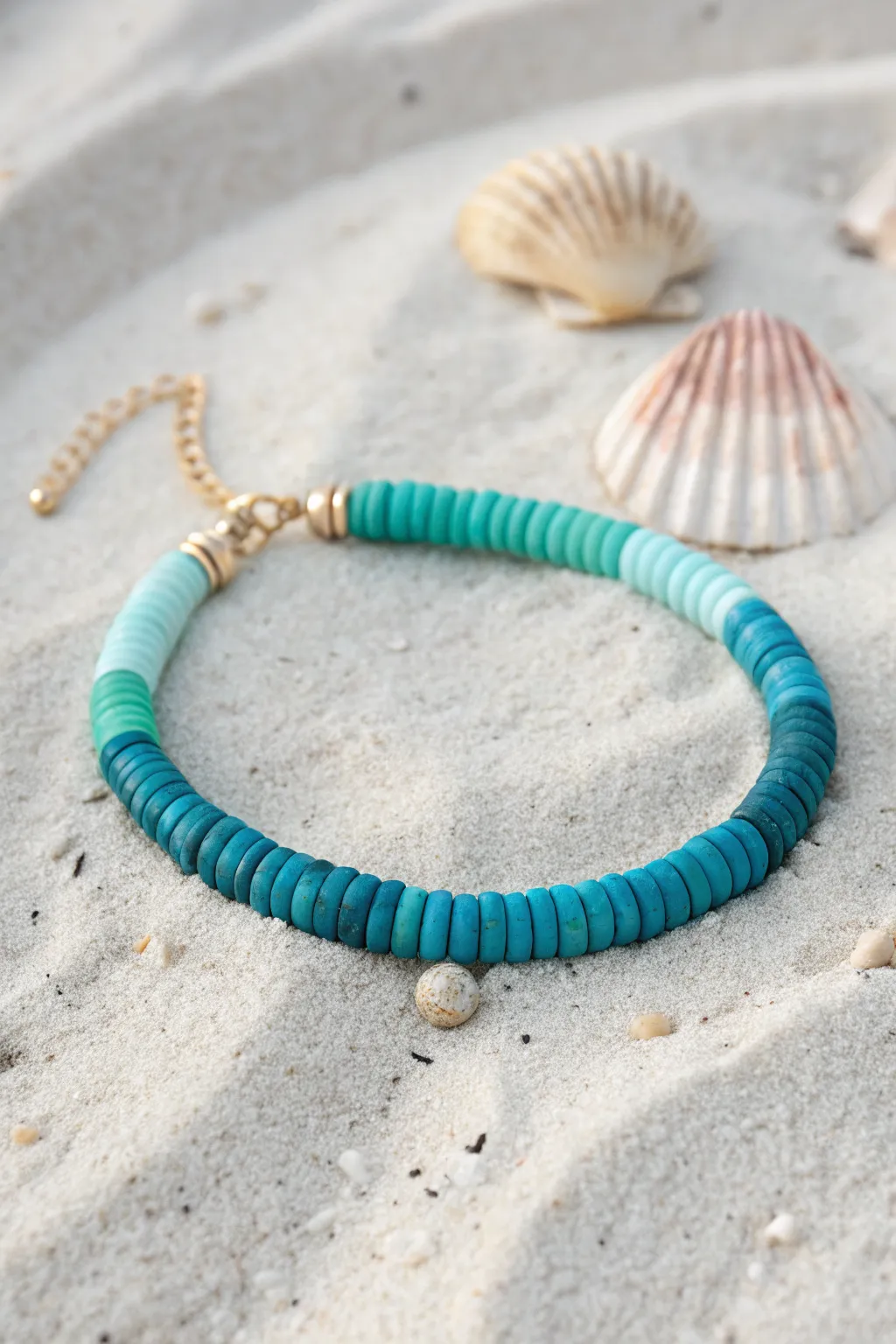 Ocean blues ombre heishi clay bracelet on sunlit sand, minimalist boho summer vibe.