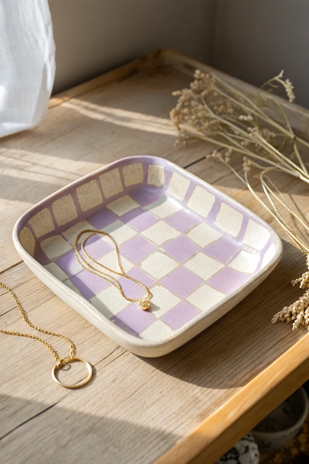 Soft lavender checkerboard clay tray with a delicate necklace, minimal Scandinavian boho styling.