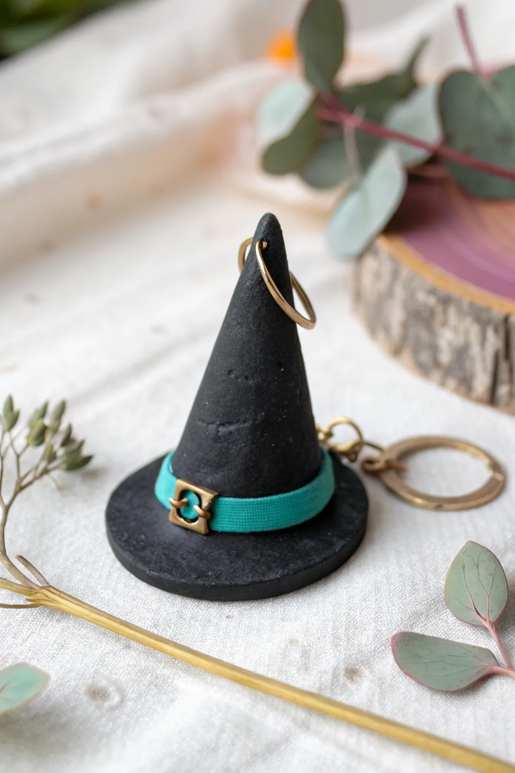 A cute mini witch hat charm in matte black clay with a bold band and tiny buckle on blush.