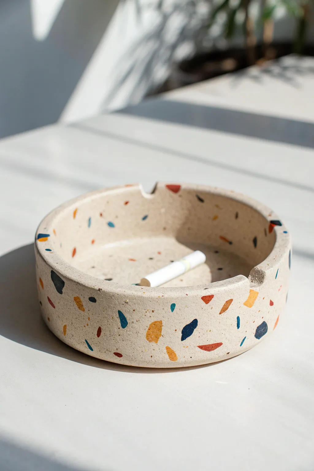 Terrazzo-speckled clay ashtray with bold color chips on a clean minimalist white backdrop