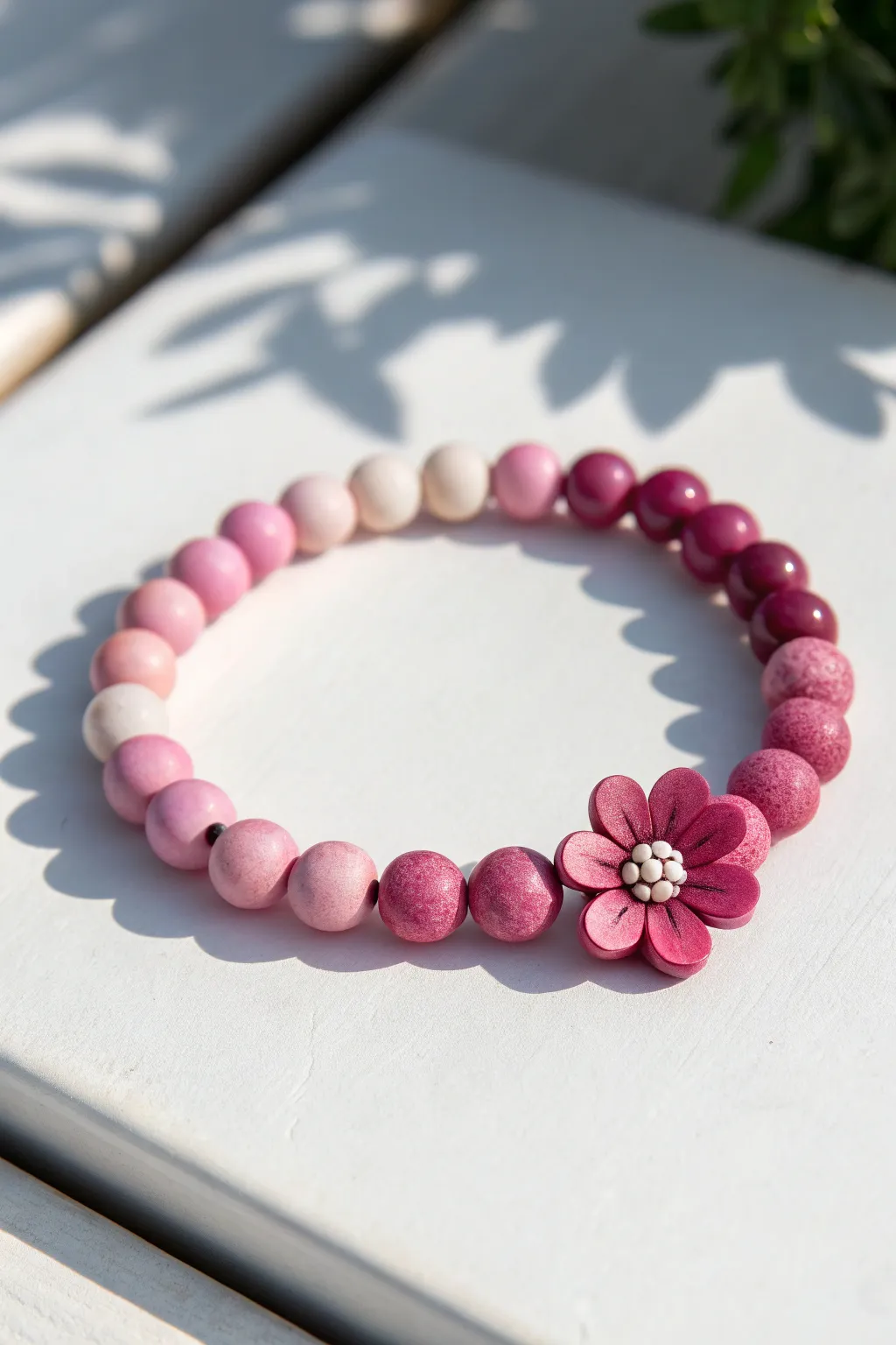 Monochrome blossom clay bead bracelet in pink ombré, minimalist flat lay with bold contrast.