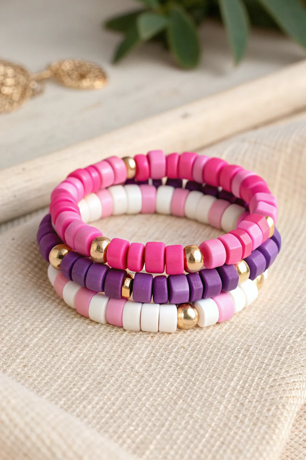 Chunky color-block clay bead bracelets in pink, purple, and white with shiny gold spacers.