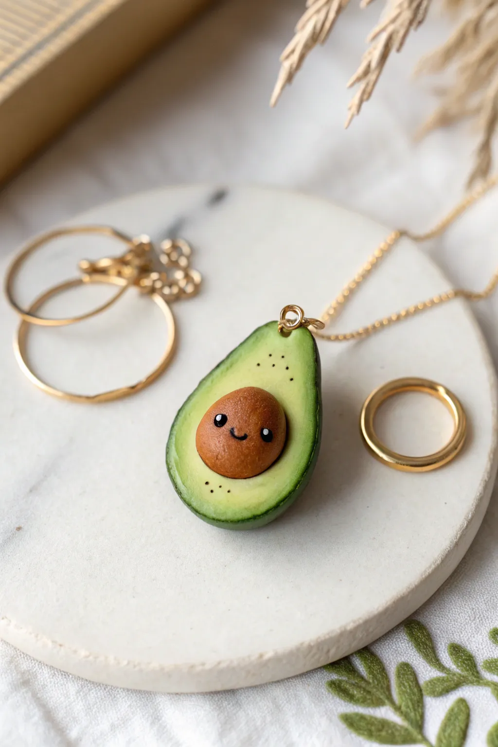 Sweet avocado half clay charm with tiny face and pit, minimalist boho styling in bold green.