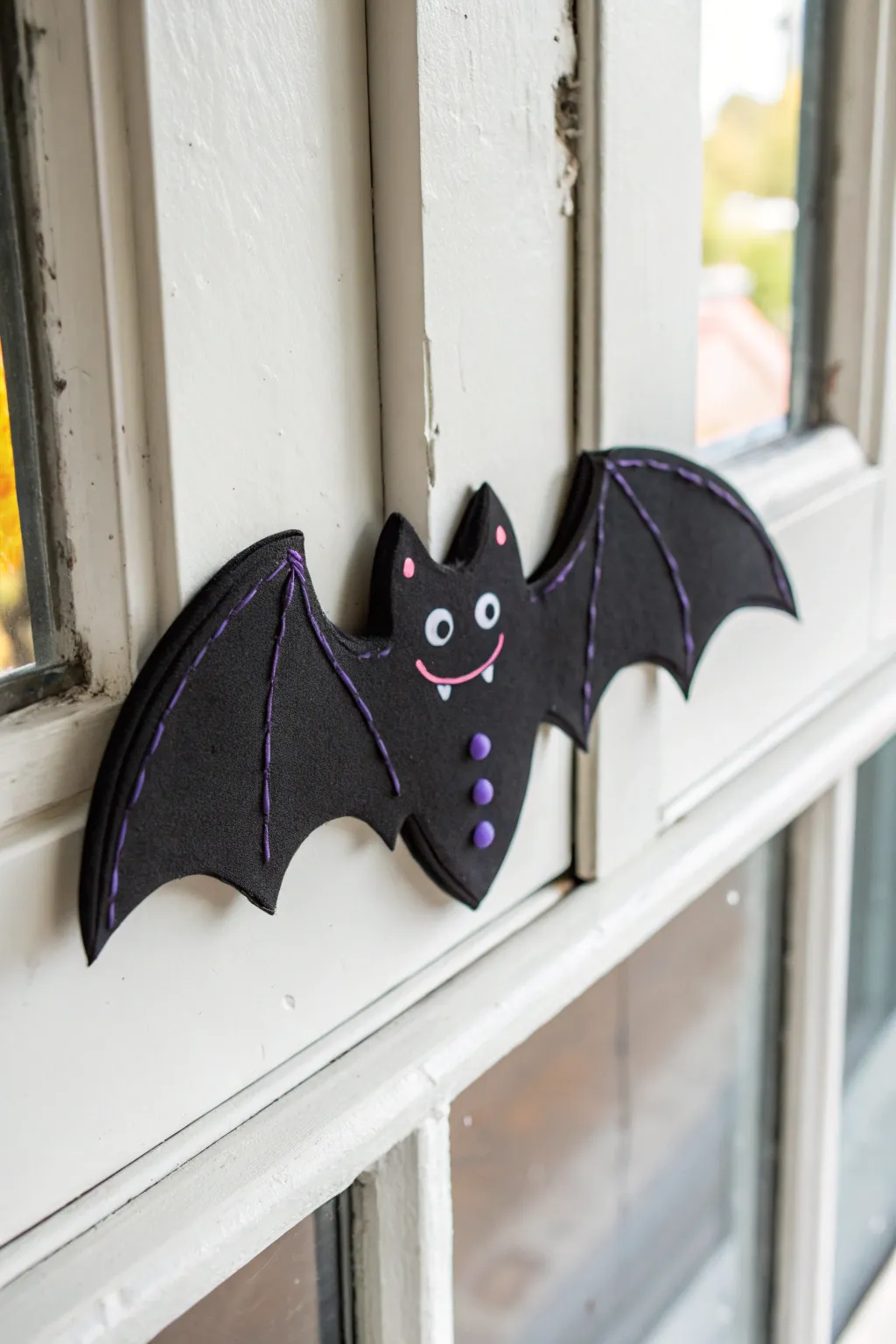 Smiling black clay bat cling with tiny purple accents, minimalist Halloween decor kids can make
