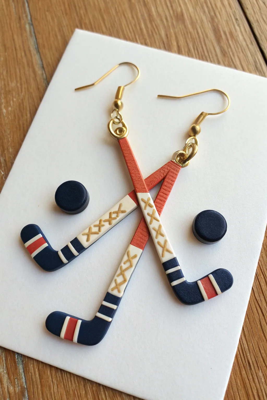 Crossed hockey sticks clay earrings with tiny puck charm, bold color pop in a clean minimalist look