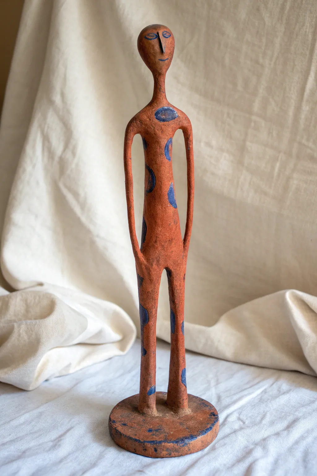 Minimal elongated standing figure in bold terracotta, a simple abstract clay sculpture idea.