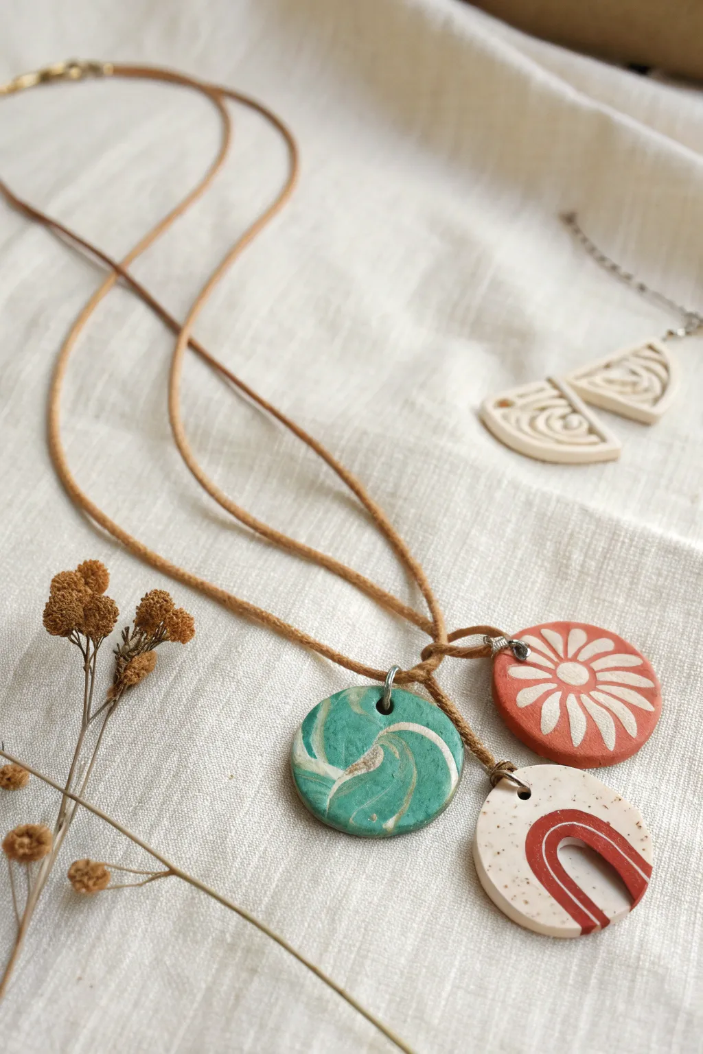 Three tiny handmade clay pendants on a simple cord, minimalist style with bold marbled color.