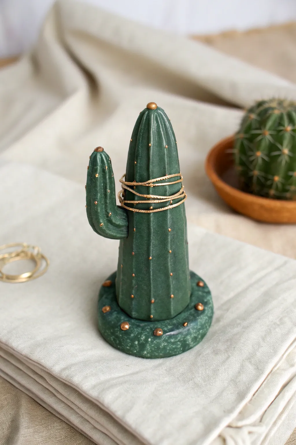 Cute chunky cactus ring holder cone in deep green clay, holding stacked rings, minimalist boho vibe.