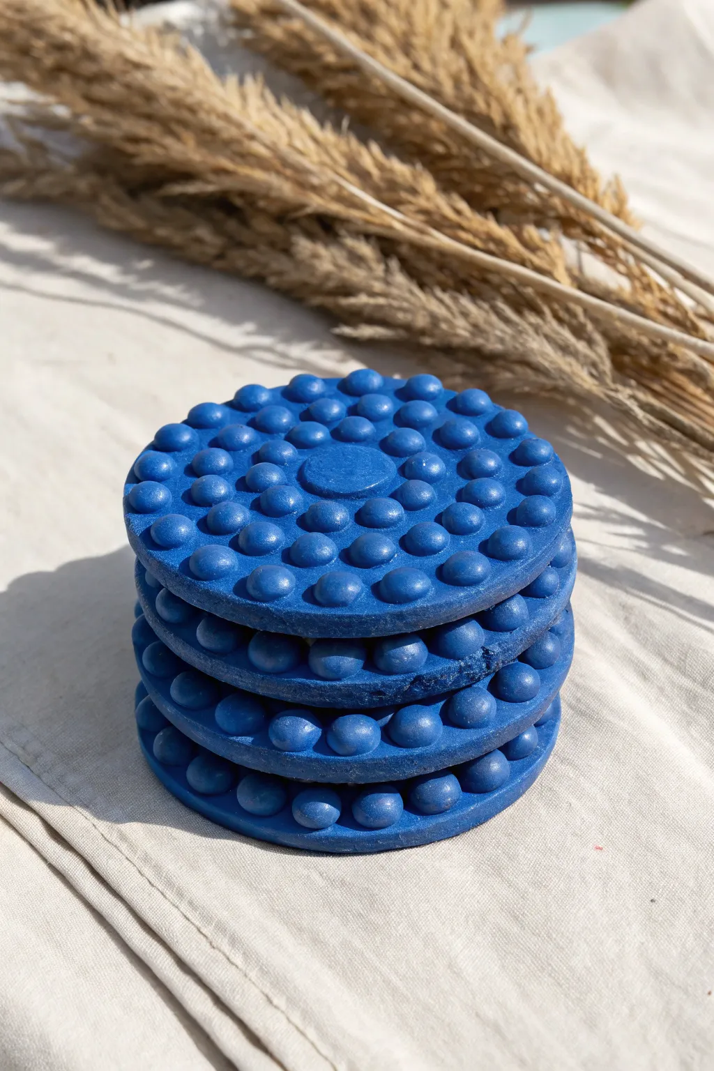Chunky bubble-textured monochrome coasters in bold cobalt, Scandinavian minimal with boho warmth