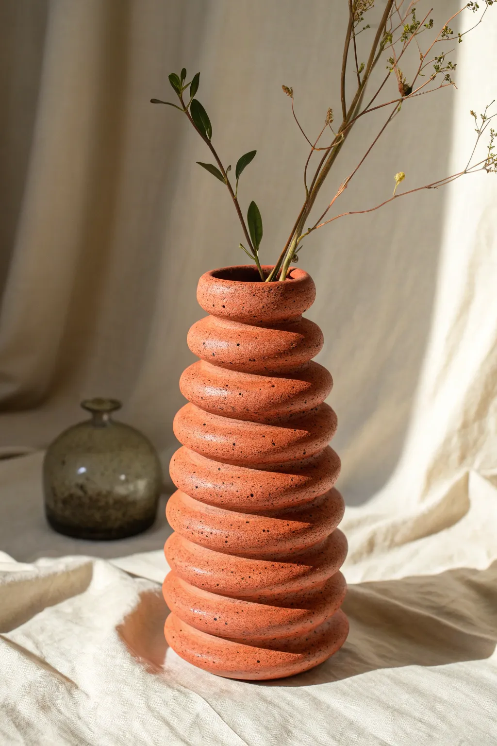 Beginner-friendly coil vase with visible ridges, styled simply with two fresh stems