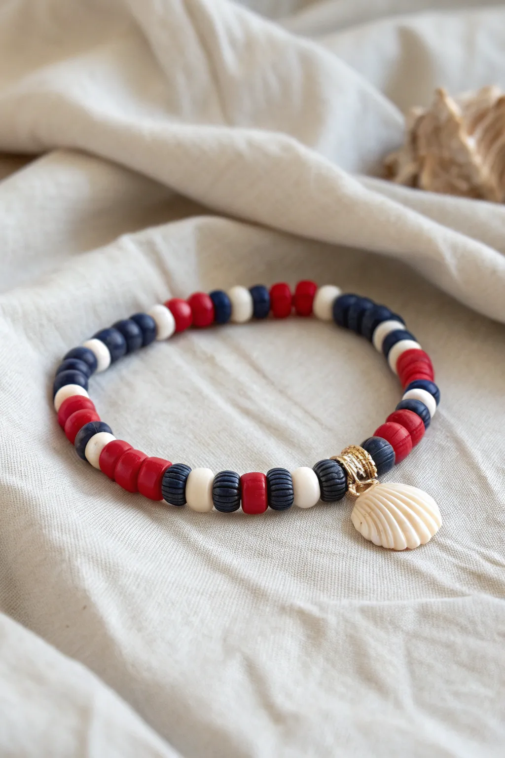 Nautical navy, red, and white heishi bracelet with a shell charm for preppy summer vibes.