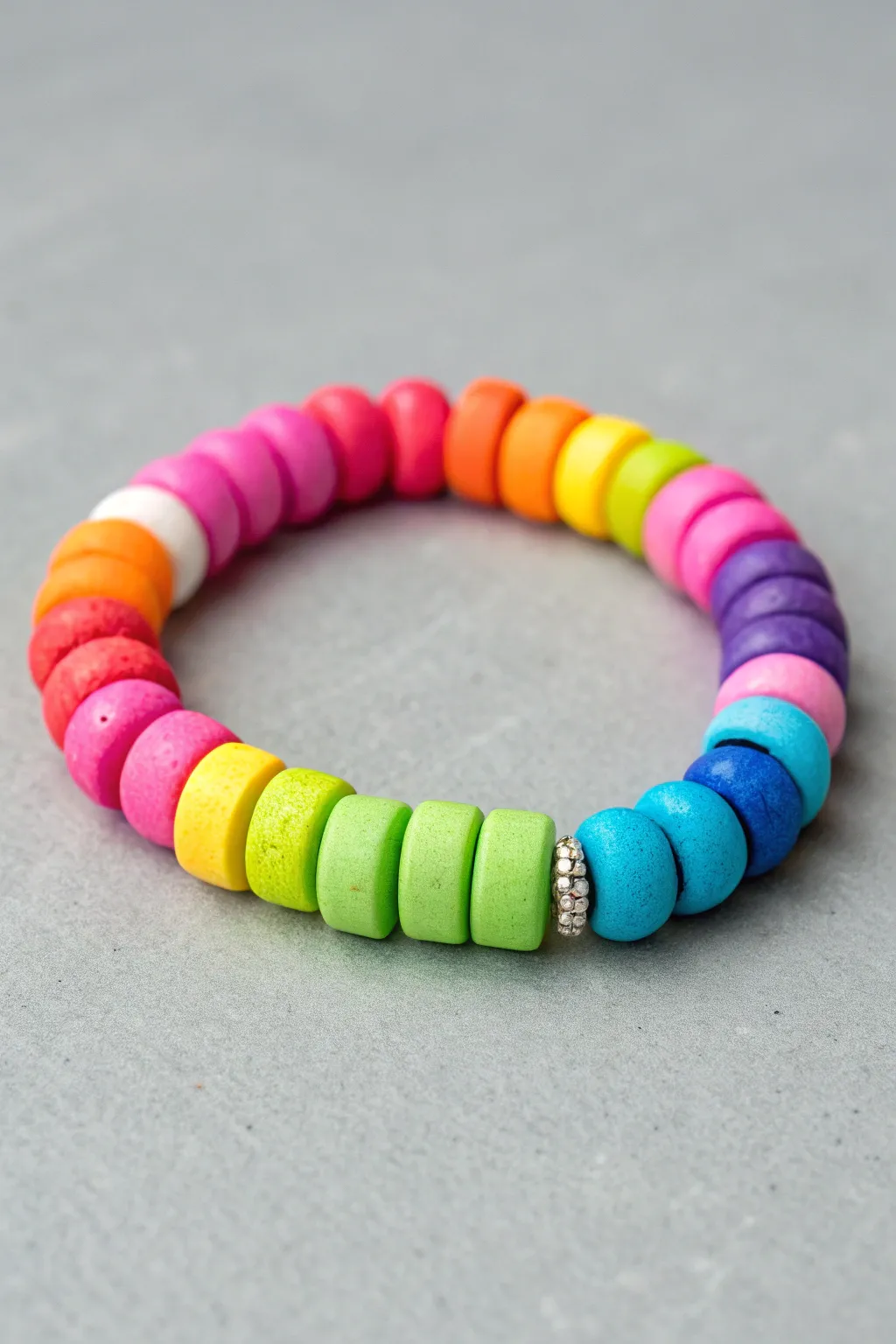 Neon rainbow clay bead bracelet on cool gray for a bold, crisp pop of color