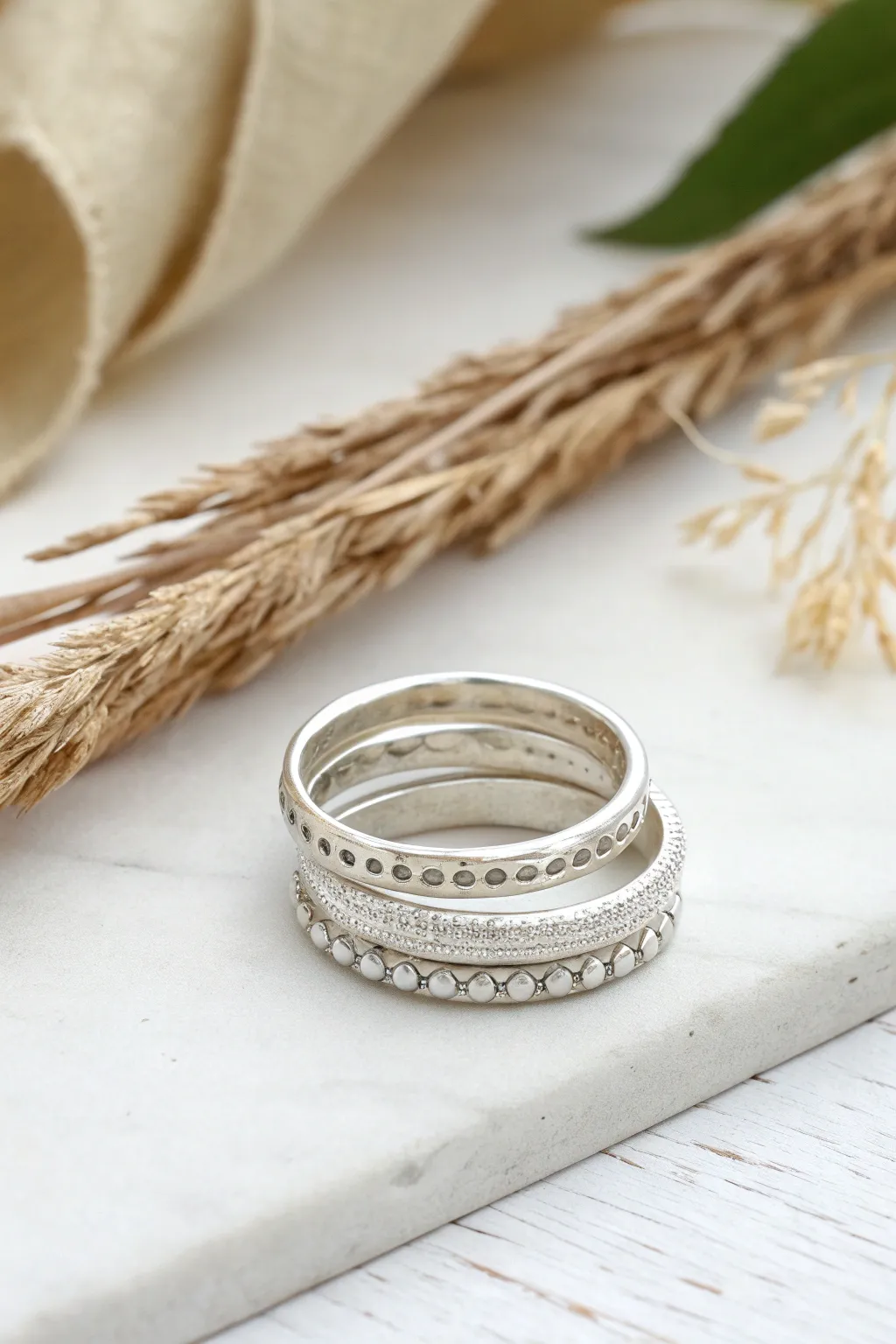 Textured silver clay stacking rings with linen, bark, and dot details in a clean minimal style.