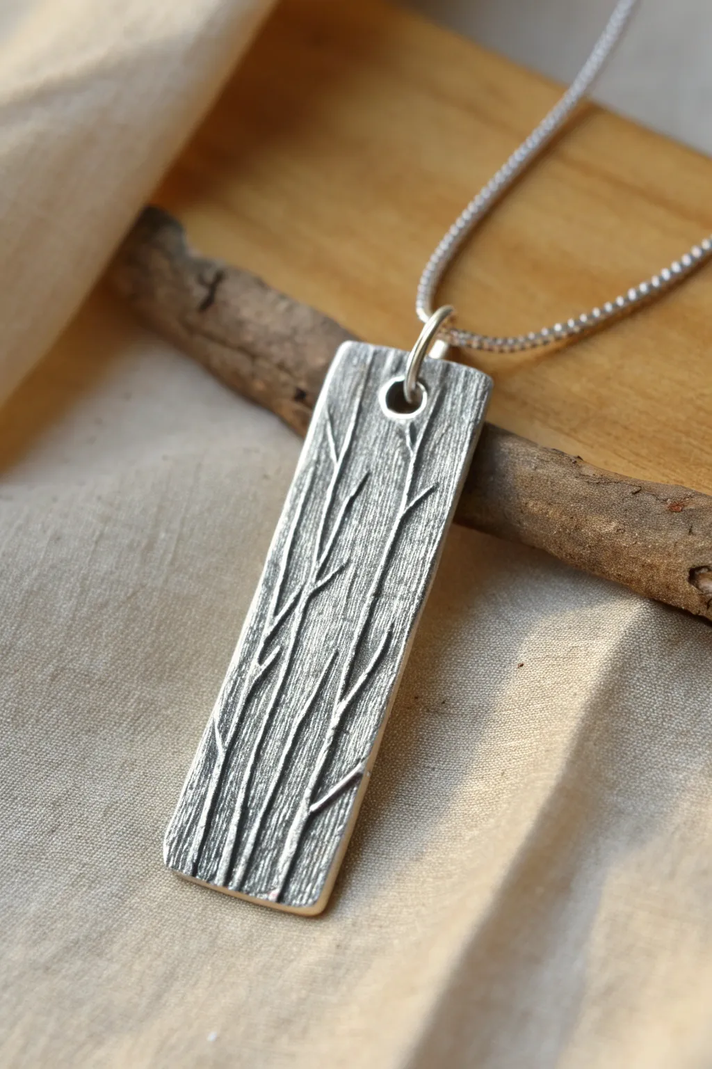 Twig and bark textured silver clay tag pendant with oxidized grooves for bold contrast