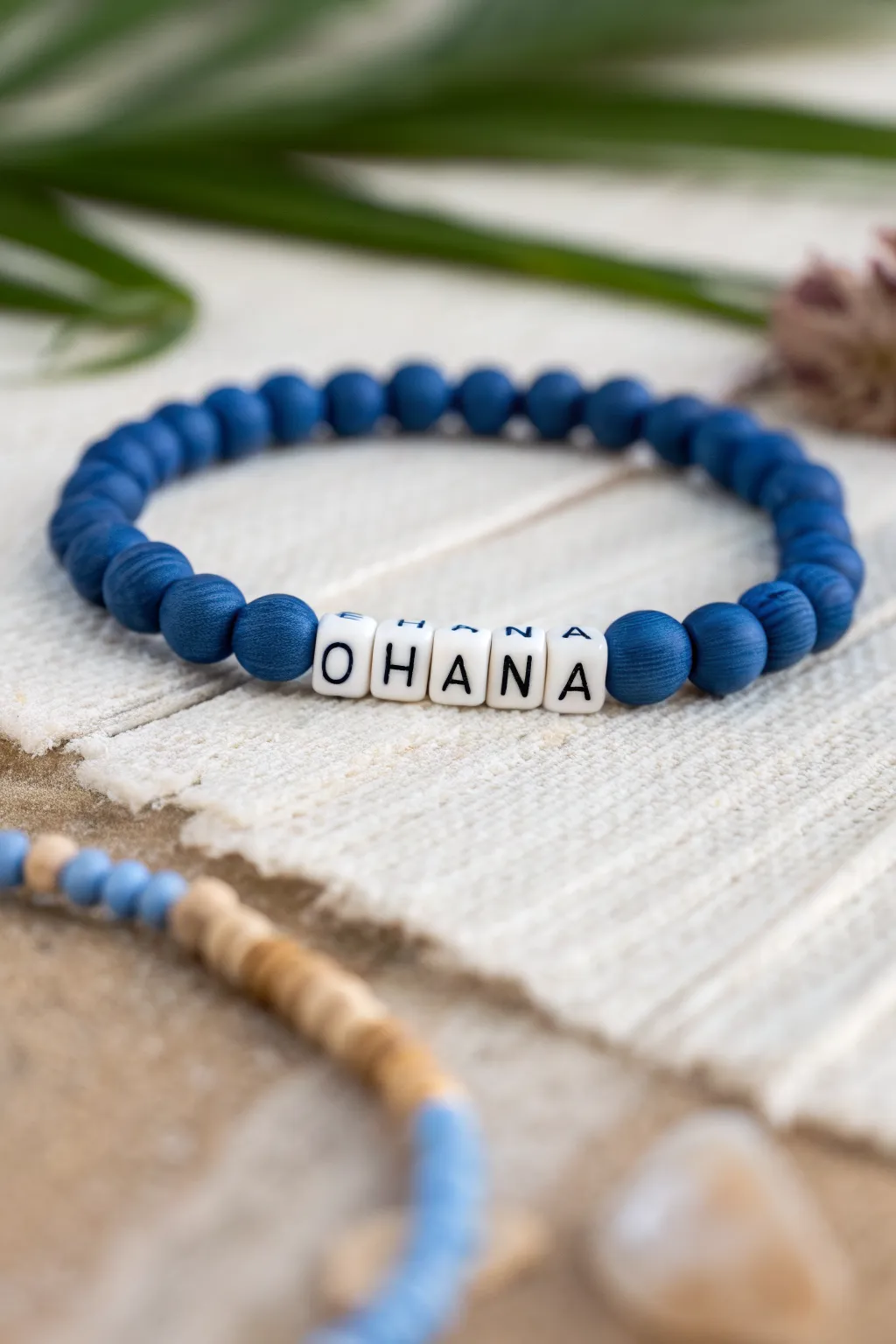 Blue heishi clay bracelet with OHANA center beads, simple symmetry and bold coastal contrast.