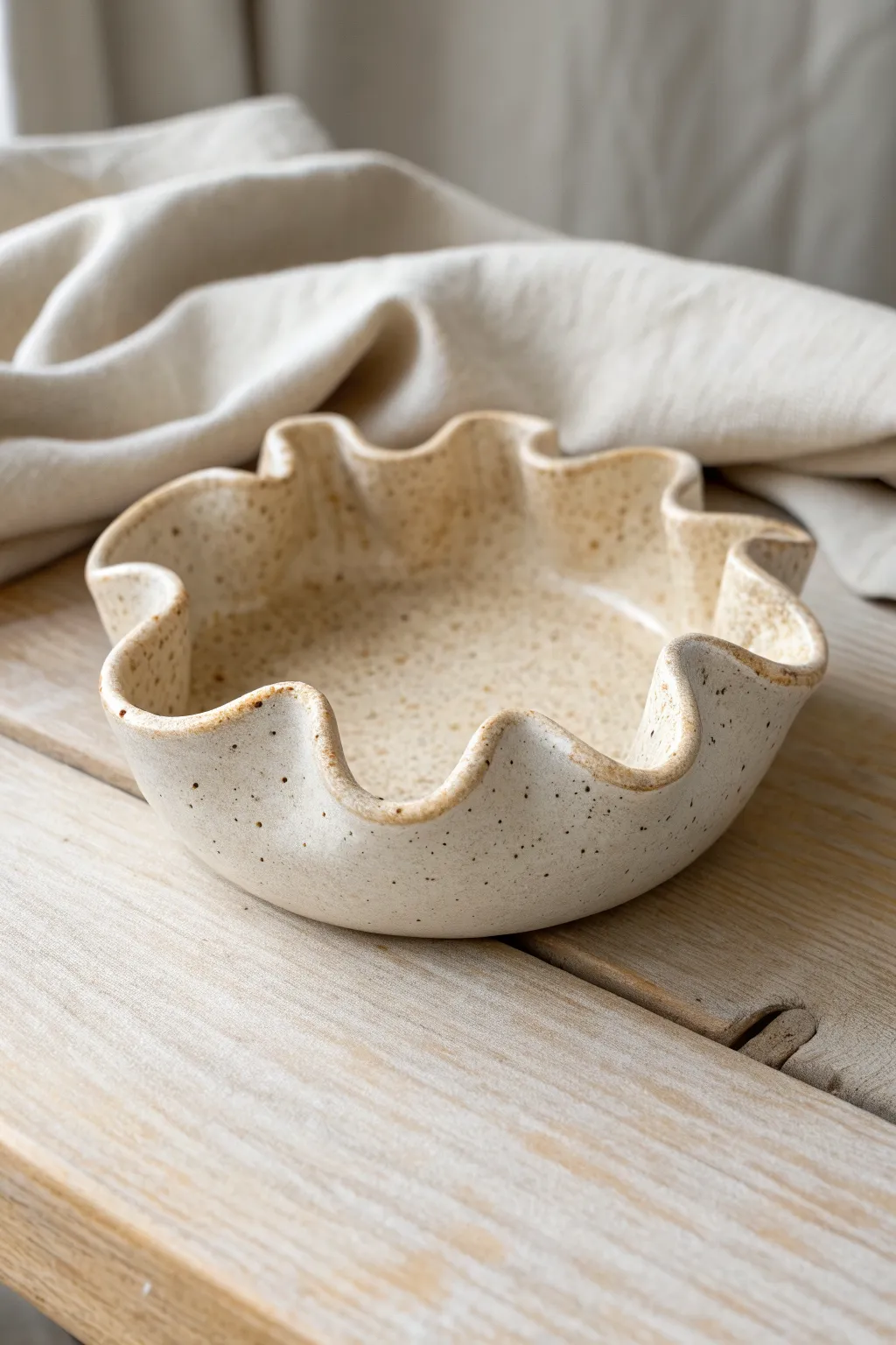 Organic blob ash tray with speckled glaze and soft wavy curves in calm Scandinavian light